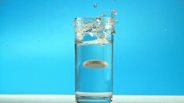 A Tablet with Splashes Falls Into a Glass of Water