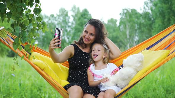 Young Woman with Daughter Take Photos in Hammock