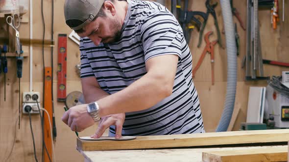 Male Carpenter with Pencil and Ruler Tracing the Cutting Line on a Wooden Detail