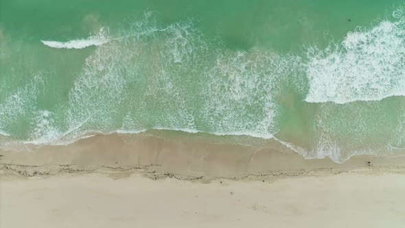 Sea with Rolling Waves and Sandy Beach. Aerial Vertical Top-Down View