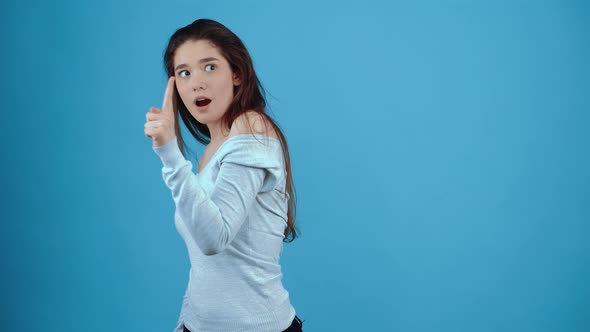 The Portrait of a Young Woman Holding Her Index Finger in Front and Opening Her Mouth in the Shape