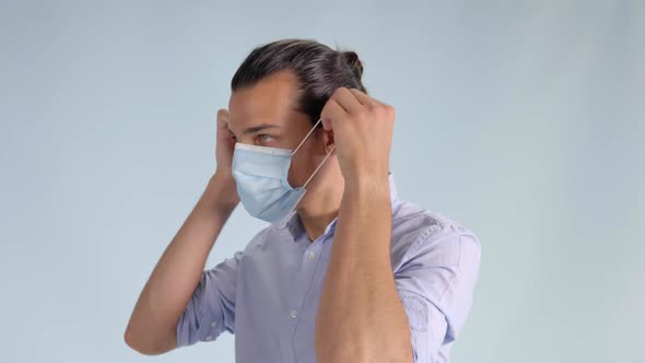 Man in Button Up Shirt Puts on Face Mask, Angled Profile Closeup Facing Left