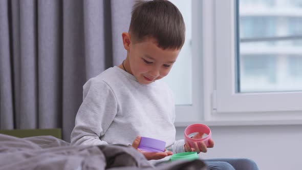 Happy Asian little boy playing with plastic toys on the bed