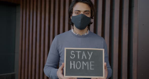 Portrait of Young Arab Man Holding Chalk Board with Stay Home Message