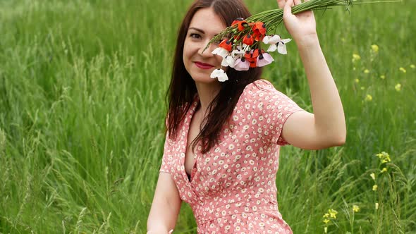 Young beautiful woman walking along a poppy field in summer. Lovely young romantic woman posing