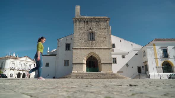 Girl Tourist Walks Through the Square of the Ancient Church of Santa Maria in the City of Faro