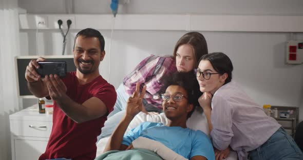 Multiethnic Young People Visiting Sick Friend in Hospital and Taking Selfie on Smartphone