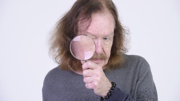 Senior Man with Mustache Using Magnifying Glass