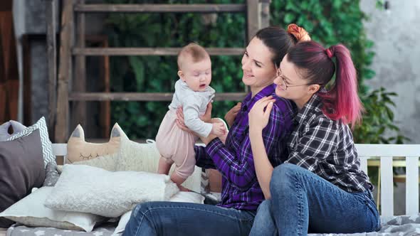 Two Happy Same Sex Parents Smiling Playing with Little Infant Daughter Enjoying Weekend