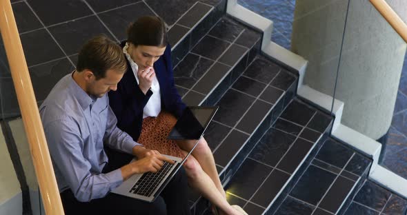 Business colleagues working on laptop and digital tablet in stairs 4k