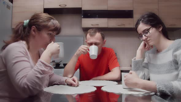 Sad Family Sitting in the Kitchen in the Evening and Silently Drinking Tea