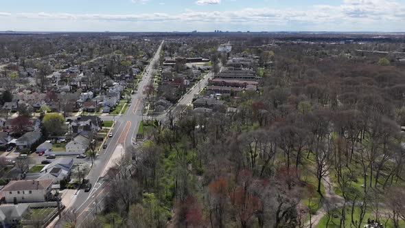 An aerial time-lapse on a sunny day with clouds flying over a park. The drone camera dolly out from