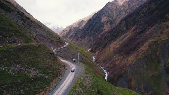 Winding Offroad Track in the Mountains and a Car Driving Through It