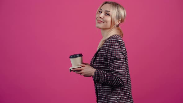 The Welldisposed Young Woman in Profile Smiles While Holding a Stand with Two Glasses of Coffee