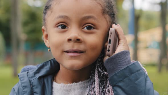 Little Girl Talking on Mobile Phone Outdoors Portrait Multiracial Child Looking at Camera Answers