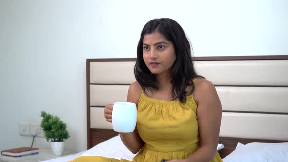 Indian woman watching TV and sipping coffee