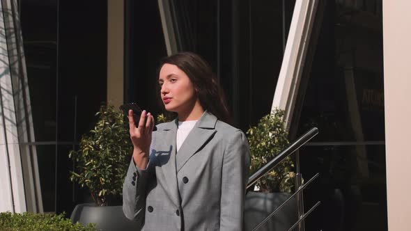 Businesswoman Talking Voice Message on a Smartphone on the Street