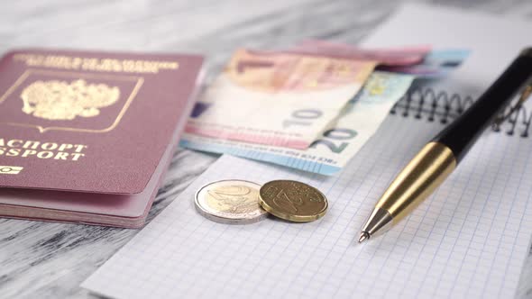 Notepad, black golden pen and red passport with dollar bills 