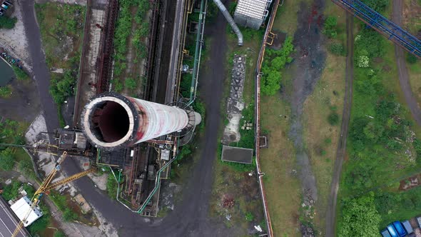 Aerial view of abandoned steel factory. Flying over and looking into chimney from left to right