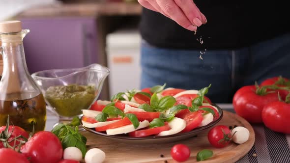 Salting Caprese Salad  Mozzarella Cheese Balls Sliced Cherry Tomatoes and Basil