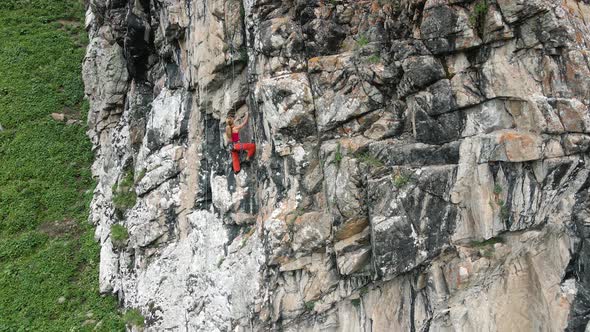 Woman Athlette Climbing on the High Rock in the Mountains