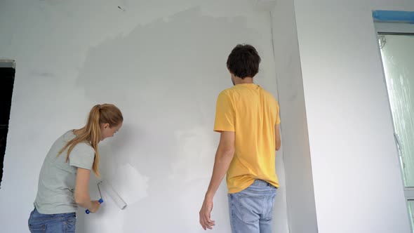 A Happy Man and Woman Paint the Wall Using a Roller Painter