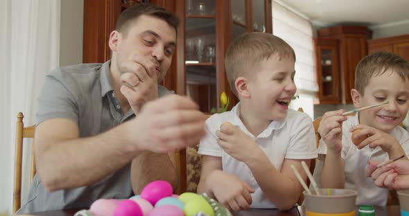 the Father with Two Sons Paints Easter Eggs