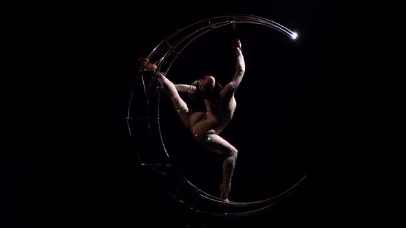 Acrobat Rotates on a Metal Structure in a Vertical String. Black Background