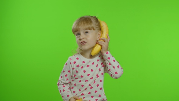 Happy Child Girl Kid Imitating Telephone Conversation with Banana Isolated on Chroma Key Background