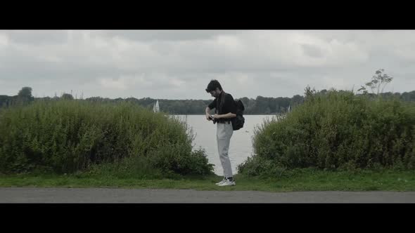 Man switching the lens on his camera in front of a lake