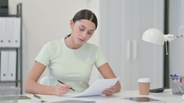 Young Latin Woman Reading Documents at Work