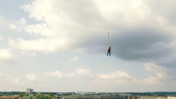 Climber Who Broke Down and Hangs on a Safety Rope Against a Cloudy Sky