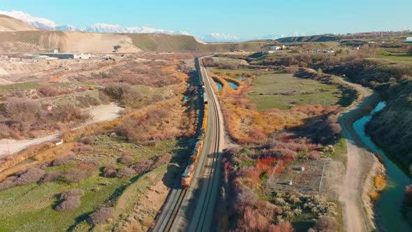 AERIAL - Train on railroad tracks close to Bluffdale, Utah, forward lowering shot