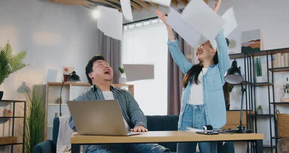Chinese Couple Celebrating Business Triumph After Getting Good News on Laptop and Giving High Five