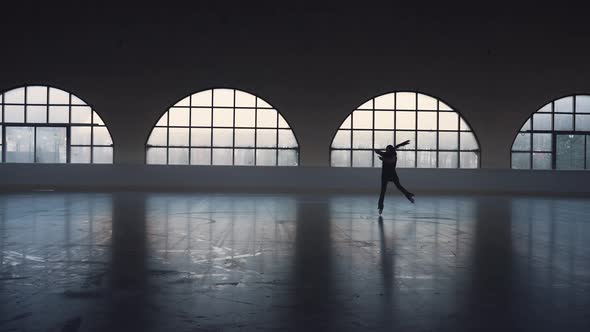 Young Woman Figure Skating Coach Skates on Dark Ice Arena