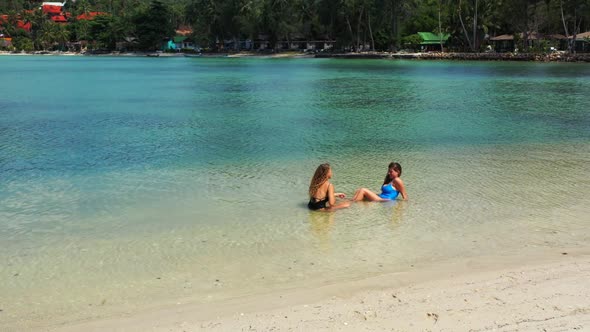 Girls happy and smiling on tropical shore beach journey by aqua blue ocean with white sandy backgrou