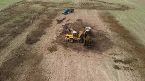 Loader Fills the Tractor's Manure Spreader in the Field