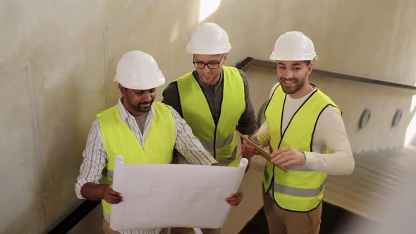 Architects in Helmets with Blueprint at Office
