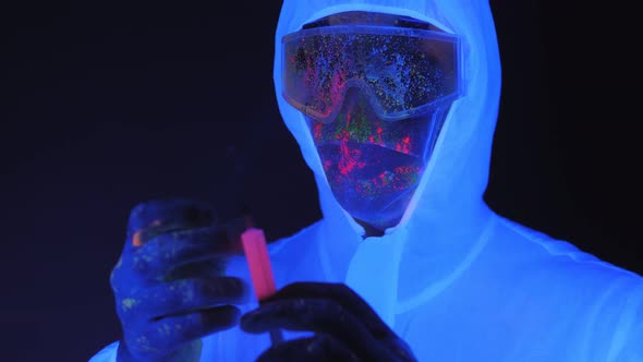 A Man in a White Suit with a Mask Splattered with UV Paint Holding a Syringe