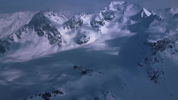 Aerial drone shot over a dark mount range landscape covered in snow above the vacation resort town o