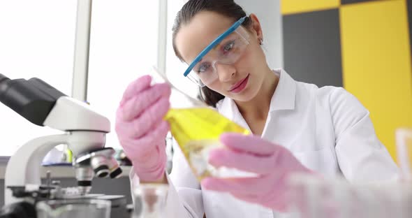 Woman Scientist Holding Yellow Glass Flask with Yellow Oily Liquid