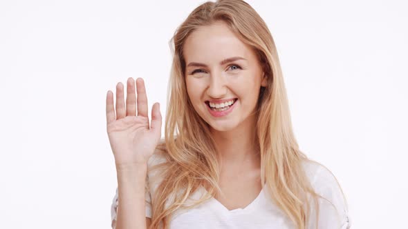 Young Beautiful Caucasian Blonde Girl Flirting Shying Waving and Covering Mouth with Hand on White