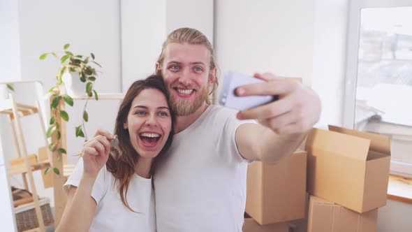 Happy Caucasian Pair Making Selfie and Posing with Keys From New Home in Slowmotion