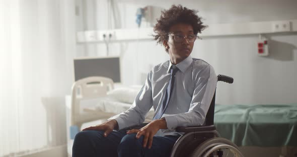 Portrait of Young Paralyzed Afro Man Sitting in Wheelchair at Hospital