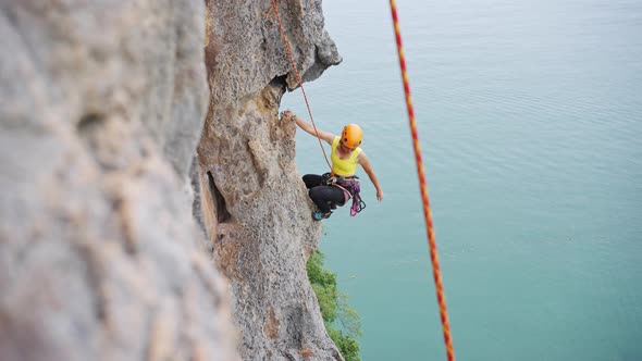 4K Mature Asian woman climbing on rock mountain at tropical island on summer vacation