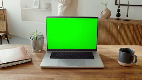An Open Laptop with a Green Screen Standing on a Table in a Home Interior