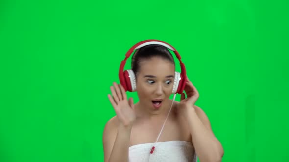 Cheerful Girl in White Towel Dancing in Big Red Headphones. Green Screen. Slow Motion