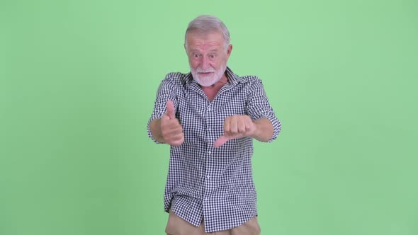 Confused Senior Bearded Man Choosing Between Thumbs Up and Thumbs Down