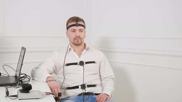 A Man Answers the Questions of the Expert Polygraph Sitting on a Chair in an Office