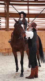 Senior Man Assisting Granddaughter Horseback Riding in Ranch